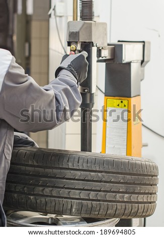 Mechanic changing car tire with bead breaker tool.