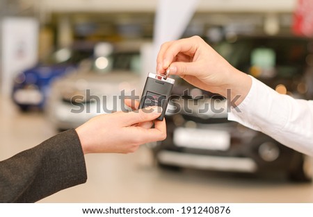 Female hand getting modern car key on several car background