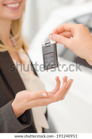 Woman getting modern car key on a car background