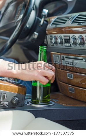 Driving Under the Influence. Female hand with bottle of beer.