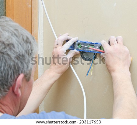 Certified electrician installing socket for light switch.