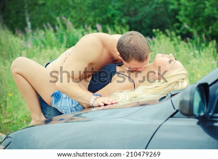 Sensual couple making love on the car\'s hood.