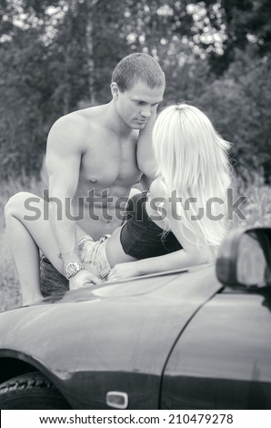 Sensual couple making love on the car\'s hood. Black and white.