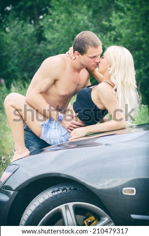 Sensual couple making love on the car\'s hood.
