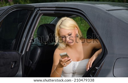 Woman with mobile phone sitting in car backseat.
