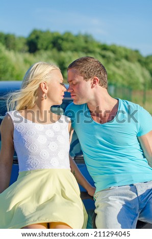 Romantic young couple kissing on the car\'s hood.