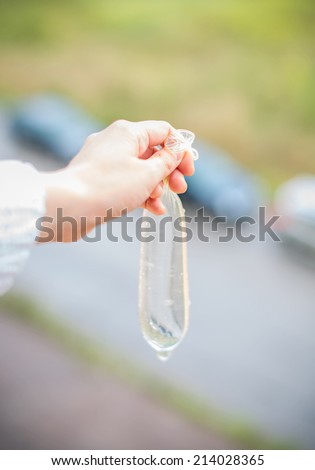 Woman\'s hand holding condom filled with water. Revenge Concept.