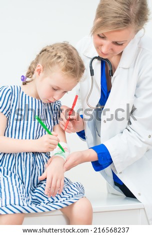 Doctor and little girl drawing bandage using felt-tip. Play therapy concept.