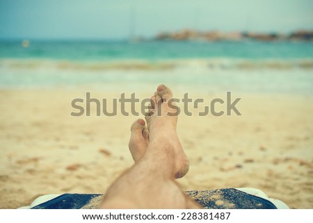 Man sunbathing on lounger. Legs. Vintage effect.