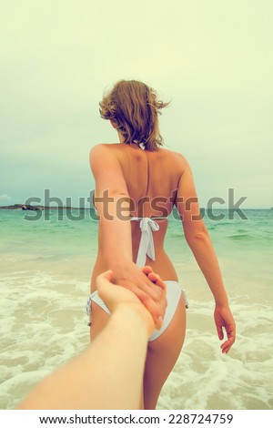 Woman holding man\'s hand and leads to the sea. Vintage effect.