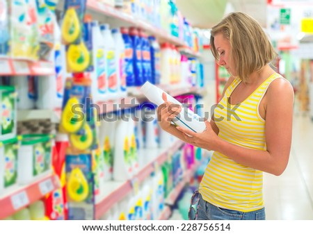Woman choosing laundry detergent in grocery store.