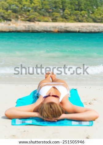 Young woman sunbathing on tropical beach.