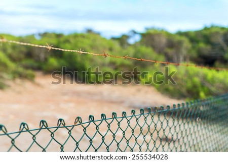 Fence with barbed wire under blue sky.