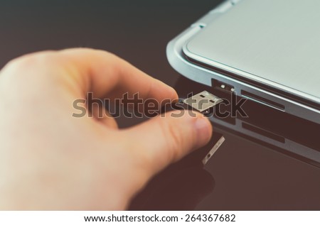 Hand plugging usb flash drive to laptop.