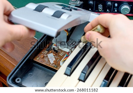 Male hand fixing midi keyboard controller.