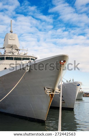 Three naval ships moored in dock.