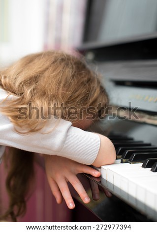 Child tired of learning the piano.