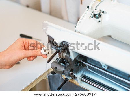 Female hand fixing sewing machine. Maintenance.