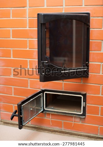 Open red brick oven with ashtray.