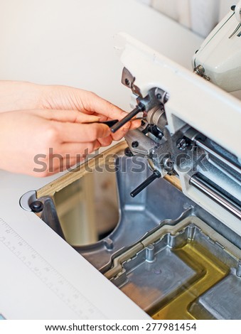 Female hand fixing sewing machine. Maintenance.