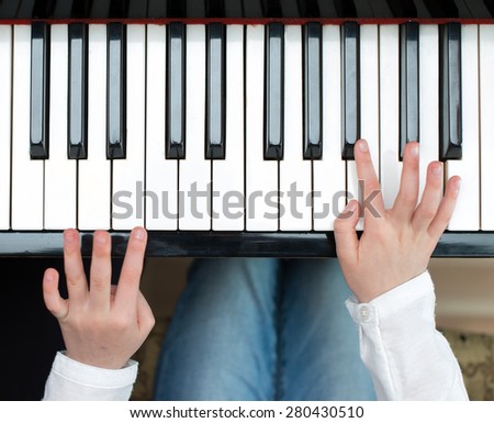 Child learning to play the piano. Top view.