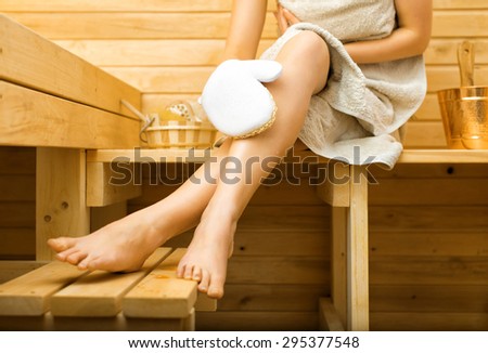 Woman relaxing in sauna. Massaging legs.