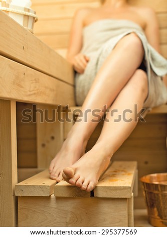 Woman relaxing in sauna. Female feet.