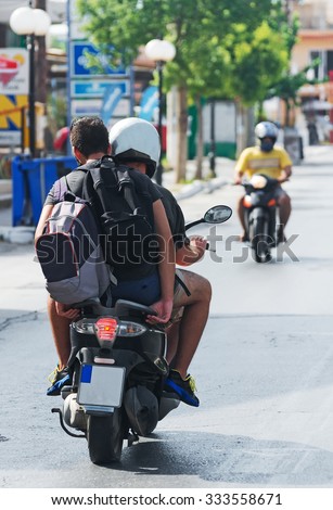 Two men with backpack on motorcycle. View from the back.