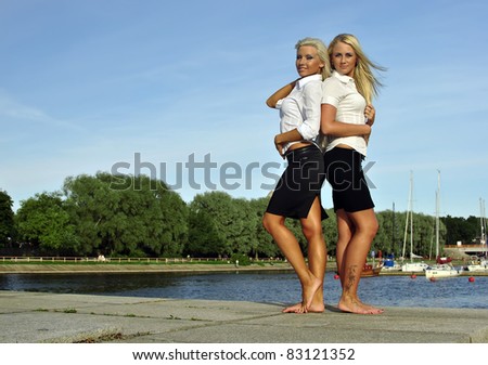 Two barefoot girls on river bank