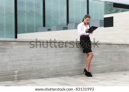 business woman in black skirt sign documents on the background of a business building