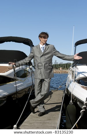 man in a gray suit, standing on the beach near the yacht