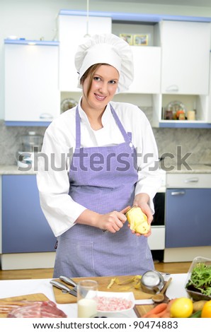 Attractive smiling chief cook preparing food, peeling potatoes
