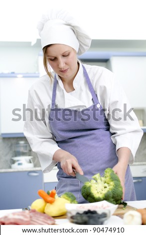 Attractive chief cook preparing food , cuts broccoli