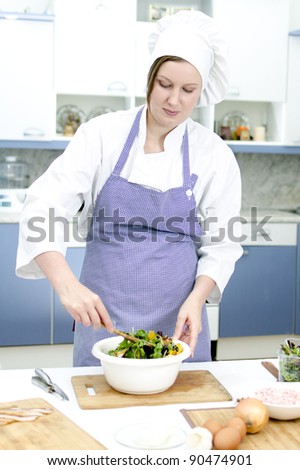 Attractive chief cook preparing salad