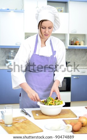 Attractive chief cook preparing salad