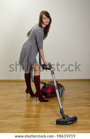 Attractive smiling girl with red vacuum cleaner.