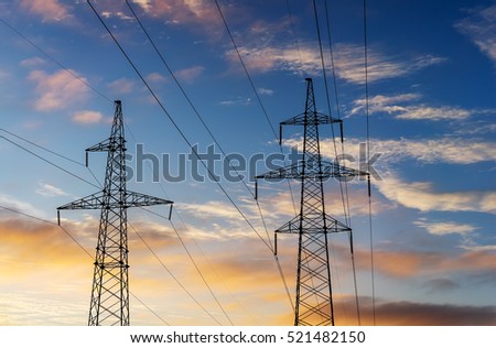 Electricity pylons and lines at dusk at sunset