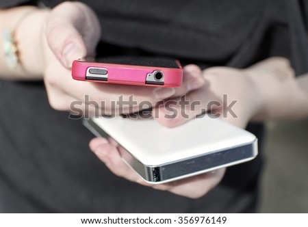 Two cell phone in the girl\'s hands with focus on the foreground