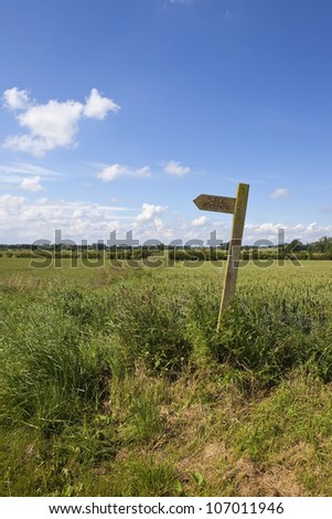 english summer landscape with a wooden footpath sign in the patchwork fields of the yorkshire wolds
