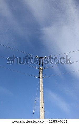 electrical power lines on a wooden pole with blue sky and wispy cloud background