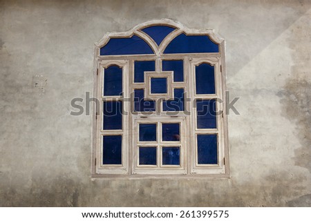 A blue timber framed traditional punjabi window set in the rendered wall of a building in a Bishnoi village