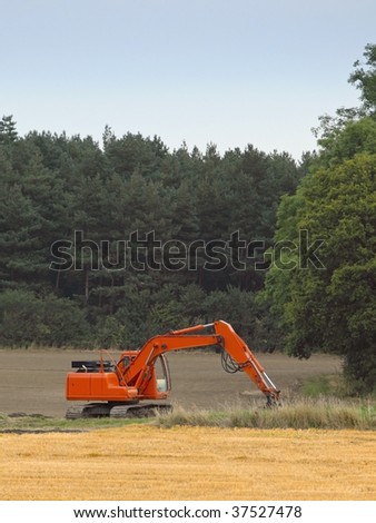 an orange digger in a field in late summer