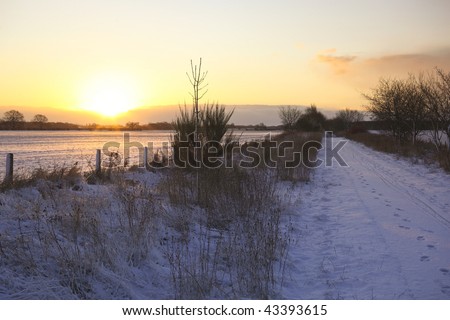 sun rising over a cycle track as a few flakes of snow fall
