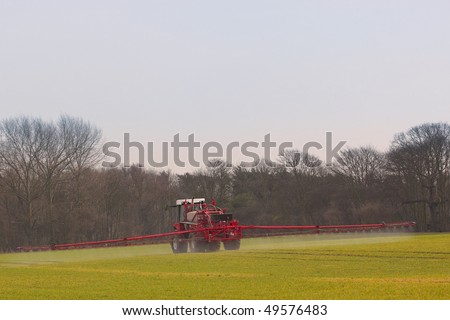 a red and white crop sprayer in action