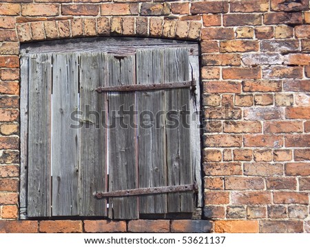 an old barn door in the side of a derelict brick building with antique hand made wrought iron crooks and bands hinges