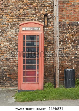a traditional red english public phone booth with old wall behind
