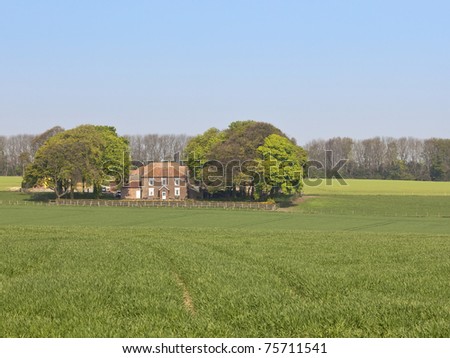 an english landscape with a farm and fields of crops in the yorkshire wolds in springtime