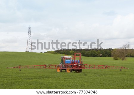 agricultural crop sprayer in action under a cloudy sky