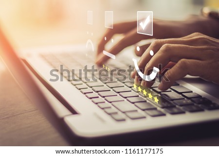 Businesswoman pressing face emoticon on the keyboard laptop / Customer service evaluation concept.