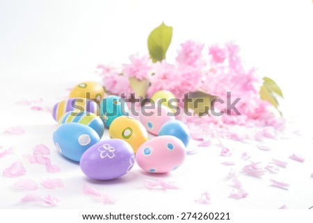 Colorful Easter eggs and pink delicate flowers brightly lit to symbolize cheerful mood and fresh beginning